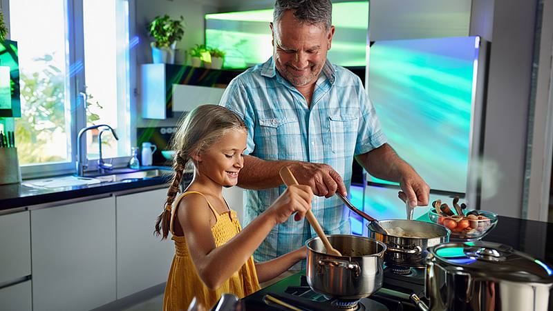 Vater kocht mit seiner Tochter in einer Küche auf einem Gasherd