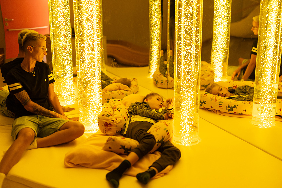 Ruheraum mit gelben Lichterketten und ruhendem Kind und seiner Betreuerin